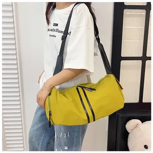 Detalle de bolso cilíndrico amarillo con cremalleras negras y correa ancha ajustable
