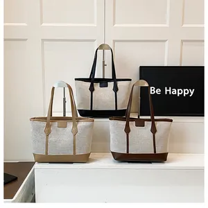 Three minimalist large capacity tote bags in canvas and leather on a display stand