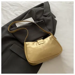 Detailed view of golden sequin shoulder bag on a dark blazer showing the metallic texture