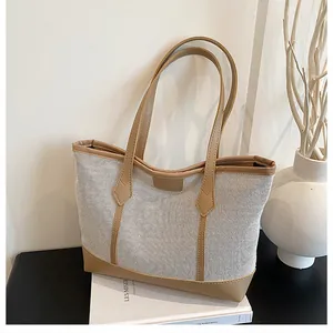 Detail of a large capacity tote bag featuring beige mesh and brown leather patchwork design