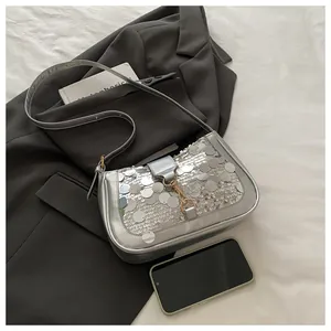 Close-up of silver sequin shoulder bag with metallic clasp and slender strap detail