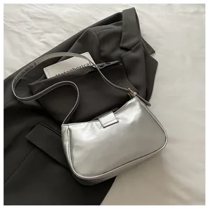 Detail of silver sequined crossbody bag with metallic finish on dark grey suit