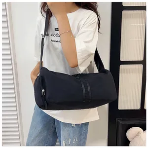 Detalle del bolso de viaje de nailon negro con tiras de cuero sintético y correa ancha