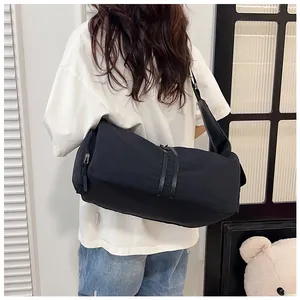 Detalle del bolso bandolera minimalista en nylon negro con vista trasera y correa al hombro
