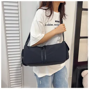 Detalle de una bolsa deportiva de nailon negro con correas decorativas y bolsillo con cremallera
