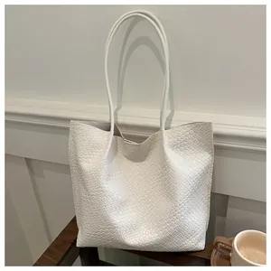 Dettaglio della trama in pelle intrecciata bianca su una borsa tote capiente da donna