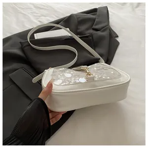 Close-up of a white sequined shoulder bag with a gold metal clasp on a black blazer