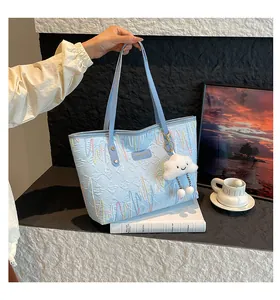 Detail of light blue tote bag featuring quilted embroidery and a cloud charm accessory