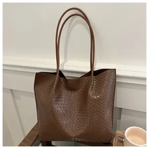 Dettaglio della trama in pelle intrecciata color caramello di una borsa tote