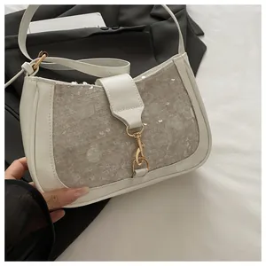Close-up of cream leather shoulder bag featuring silver sequins and gold metal buckle detail