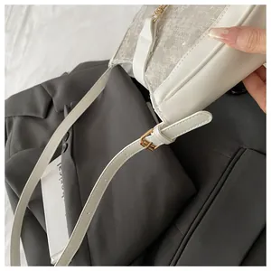 Detail of cream white crossbody bag featuring mixed fabric textures and gold metal buckle