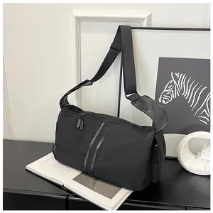 Detalle de bandolera de nailon negro con cremalleras dobles y correa ancha acolchada para hombro