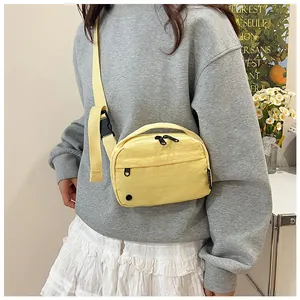 Detail of yellow nylon crossbody bag featuring multi-zipper pockets and adjustable strap