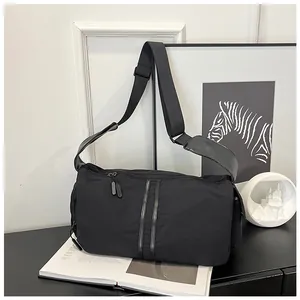 Detalle del bolso bandolera de nailon negro con cremalleras dobles y correa ancha ajustable