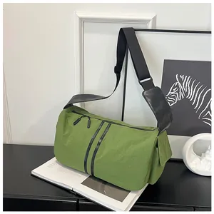 Detalle del bolso bandolera de nailon verde claro con cremalleras negras y correa