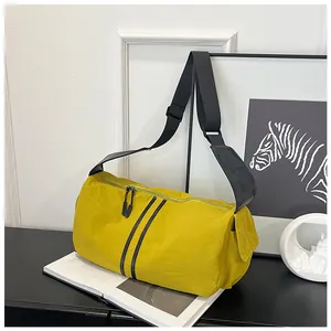 Detalle del bolso bandolera cilíndrico de nailon amarillo mostaza con correas negras