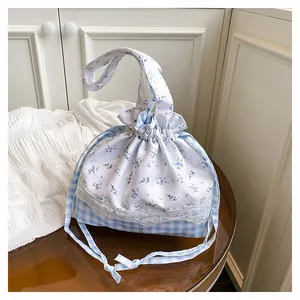 Detail of blue floral and plaid patchwork drawstring bag with delicate lace trim