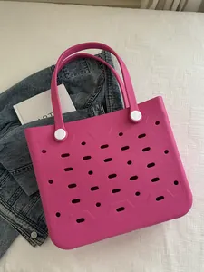 Flachbild einer pinken EVA-Strandtasche mit Lochmuster neben einer Jeansjacke