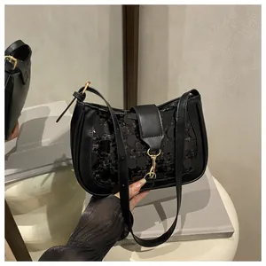 Close-up of black sequined crescent bag with gold metal hooks and smooth leather details