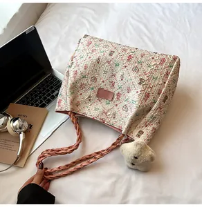 Detail view of pink floral puff tote bag with plush star charm on white linen