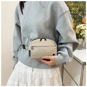 Detail of adjustable gray strap and black buckle on off-white nylon crossbody bag