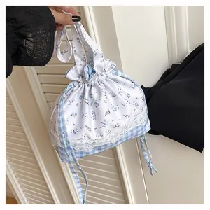 Detail of drawstring lunch bag featuring floral lace and blue checkered fabric patterns