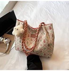 Floral tote bag with pink straps, bear pattern, and star charm on a bed background