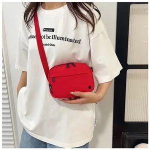 Close-up of red waterproof nylon crossbody bag showing zip pocket and branding detail