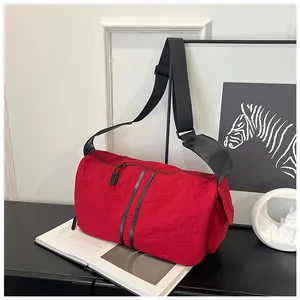 Detalle de un bolso bandolera rojo con textura arrugada y correas negras