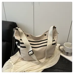 Détail d'un sac à bandoulière en toile beige avec rayures noires et large sangle