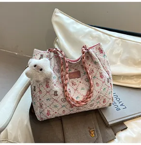 Detail of white textured tote bag featuring pink floral bear print and plush charm