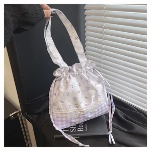 Detail of floral and purple checkered drawstring bag with lace patchwork on a book