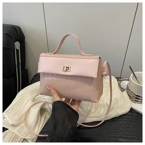 Detail of pink houndstooth embossed square bag featuring a gold twist-lock and handle