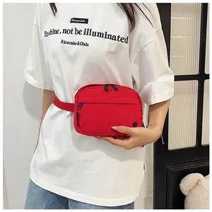 Detail of red nylon crossbody bag showing dual zippers and adjustable strap on waist