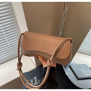 Close-up of khaki PU leather underarm bag featuring a knotted strap and flap design
