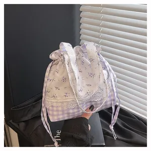 Detail of drawstring handbag featuring purple floral and plaid patchwork with lace trim