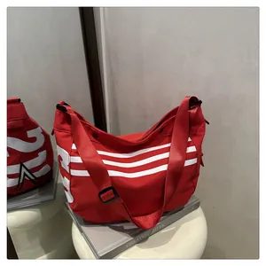 Vue détaillée du grand sac cabas en nylon rouge avec bandes blanches et texte