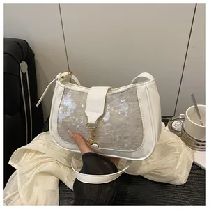 Close-up of white sequined crescent bag with elegant gold metal clasp and leather buckle