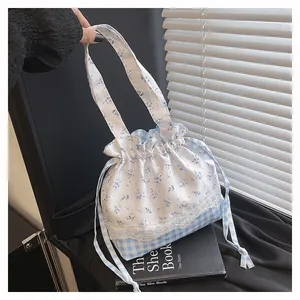 Detail of floral and gingham drawstring bucket bag with delicate white lace trim