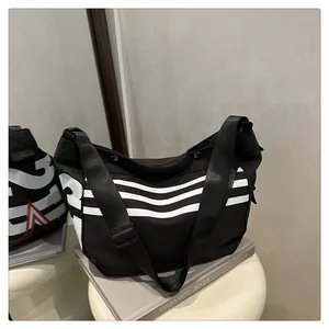 Détail du sac messager en toile noire avec rayures blanches et bandoulière réglable
