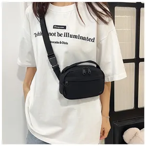 Close-up of minimalist black nylon crossbody bag with adjustable wide strap and buckle