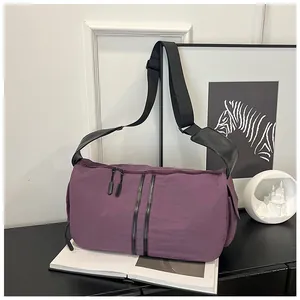 Vista de detalle del bolso bandolera de nailon morado oscuro con rayas negras y correa