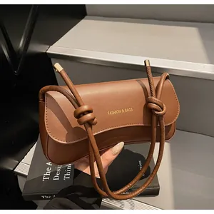 Detail of a brown vintage underarm bag featuring knotted straps and golden logo