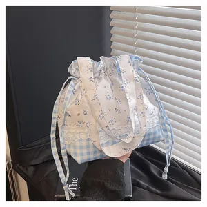 Detail of floral and plaid patchwork bucket bag with delicate lace trim and drawstring closure