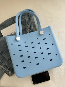 Detailansicht der hellblauen EVA-Strandtasche mit ovalen Löchern und weißer Schnalle auf Tisch