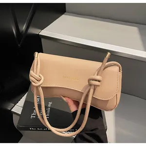 Detail of beige leather bag featuring knotted shoulder strap and gold metallic clasp