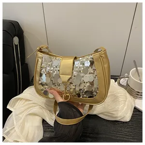 Close-up of golden sequin shoulder bag with metallic clasp and faux leather strap detail