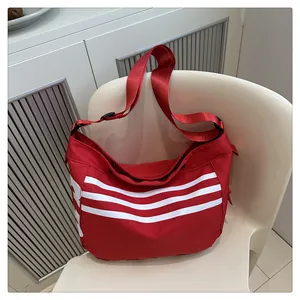 Gros plan détaillé d'un sac bandoulière rouge en nylon avec rayures blanches sur chaise blanche
