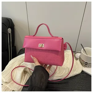 Detail of rose red handbag with embossed texture, gold twist lock and elegant top handle