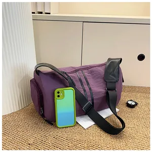 Detalle del bolso de viaje morado impermeable con correas negras y hombrera acolchada